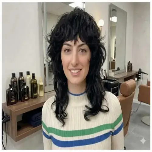 Woman with a Collarbone-Length Wolf Cut featuring voluminous layered curls, shaggy bangs, and textured ends, showcasing the haircut's signature movement and shape in a modern salon setting.