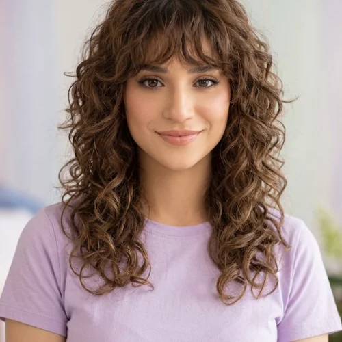 Woman with a long curly wolf cut and wispy full bangs.