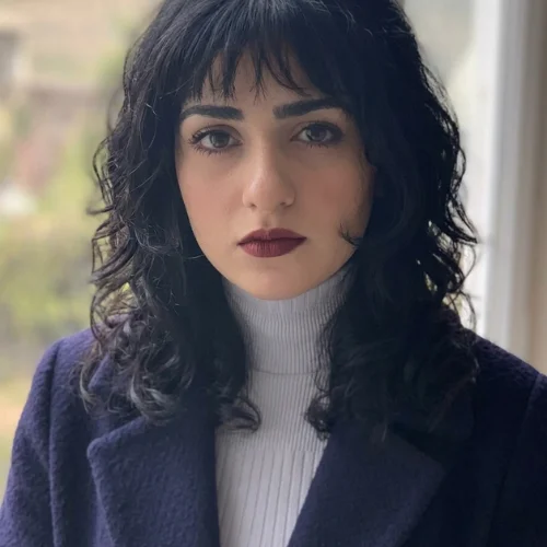 "Korean wolf haircut for curly hair with soft shaggy layers, wispy micro bangs, and natural textured curls framing the face."