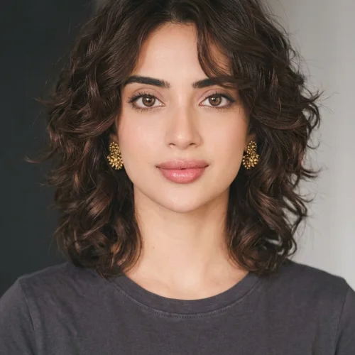 Woman with a voluminous curly bixie bob haircut styled with middle-parted curtain layers.